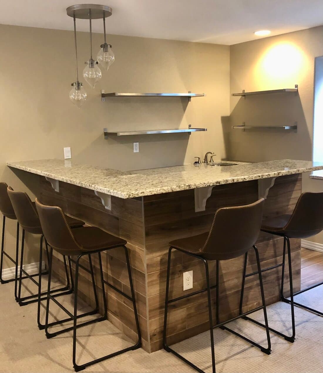 Custom wet bar with granite countertop and reclaimed-wood base