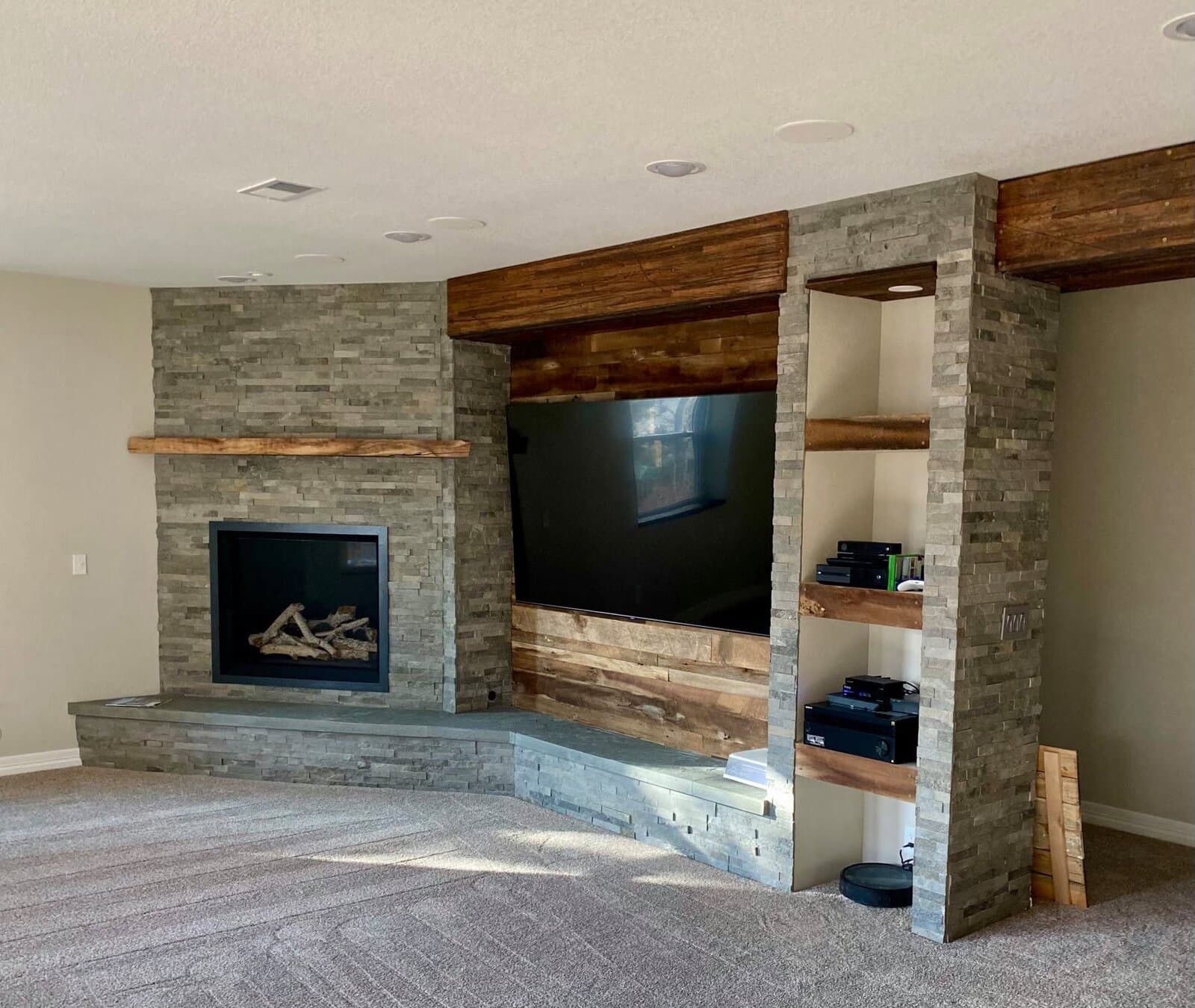 Stacked-stone fireplace and reclaimed-wood entertainment wall with built-in shelving