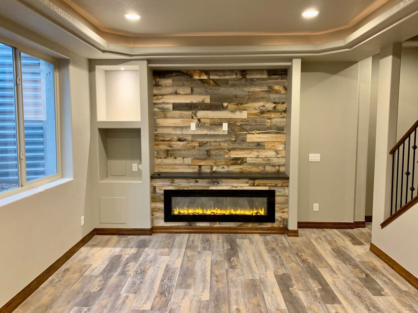 Finished basement living room with stacked-stone fireplace and tray ceiling