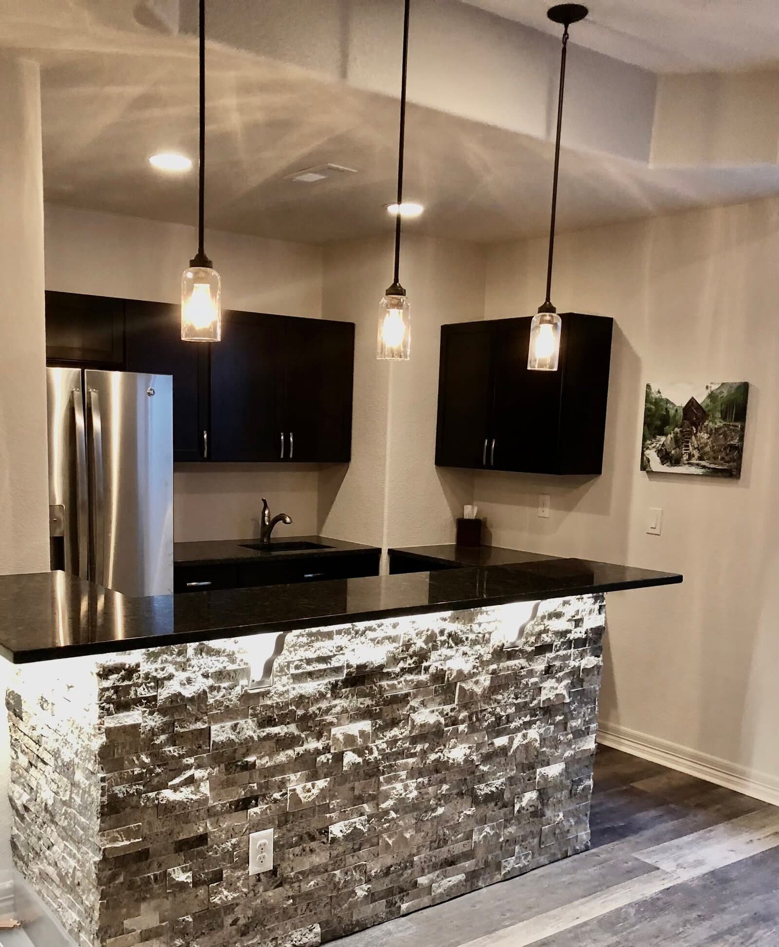 Modern basement kitchen bar with stacked-stone island and pendant lighting